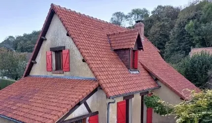 Après : la même toiture nettoyée, tuiles rouges à nouveau visibles