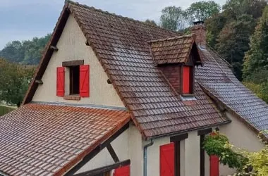 La même toiture en tuiles avant nettoyage, couverte de mousses et de salissures